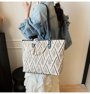Detail of geometric woven tote bag with leather straps and pearl lace pendant