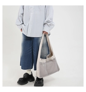 Gros plan sur le sac fourre-tout en filet gris avec bandoulière large pour le quotidien