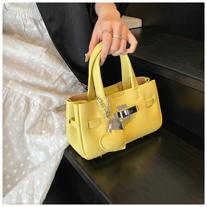 Détail du sac à main en cuir grainé jaune avec fermoir argenté et charm coeur