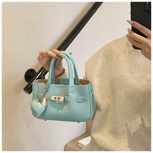 Gros plan du sac en cuir bleu clair avec fermoir argenté et pendentif cœur