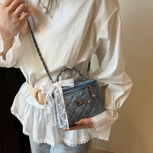 Retro denim quilted box bag with white lace bow and chain strap on female model