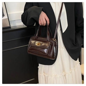 Detail of dark brown retro leather handbag with metal twist lock and shoulder strap