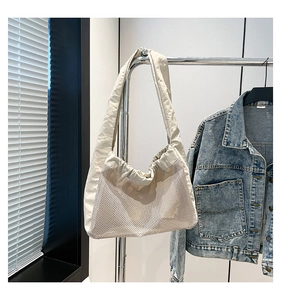 Détail du sac fourre-tout en maille blanc cassé avec texture aérée et anses en tissu