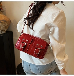 Dettaglio borsa a tracolla in pelle verniciata rossa con fibbie argentate su camicia