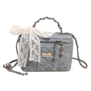 Light blue denim box bag with quilted stitching, chain handle and white lace bow