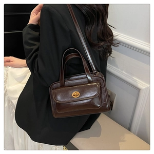 Detail of vintage coffee oil-wax leather handbag with golden clasp shown on shoulder