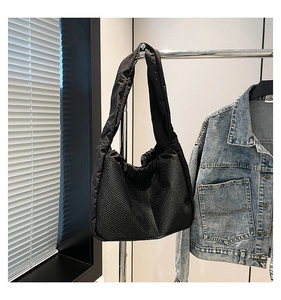 Détail du sac en maille noire avec bandoulières rembourrées près d'une veste en jean