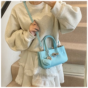 Détail du sac à main en cuir grainé bleu ciel avec fermoir argenté et breloque coeur
