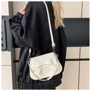 Detail of cream white crossbody bag with large bow and pearl metal chain strap
