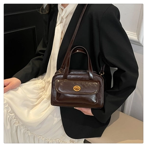 Close-up of a dark brown glossy retro handbag with gold metallic twist-lock detail