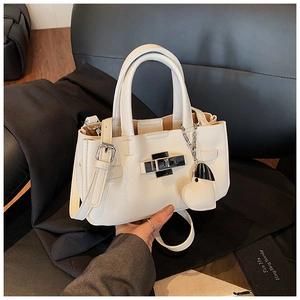 Détail d'un sac à main en cuir litchi blanc avec fermoir argenté et breloque cœur