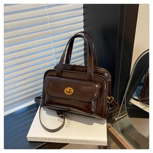Detail of a vintage dark brown high-gloss leather handbag with gold twist lock