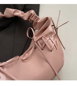 Gros plan du sac à bandoulière plissé rose avec laçage décoratif latéral en similicuir souple
