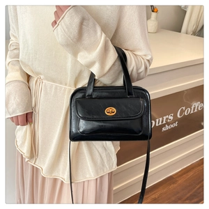 Close-up of a vintage black crossbody bag with a gold metal clasp and matte finish