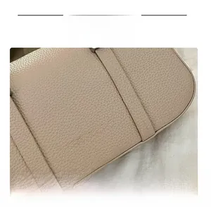 Detail of light beige litchi grain leather texture and silver printed brand lettering