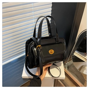 Detail of black glossy vintage handbag featuring gold twist lock and fine leather texture