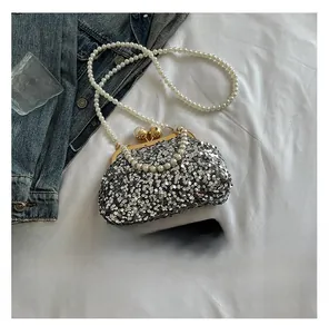 Détail d'un sac de soirée argenté à paillettes avec fermoir et bandoulières en perles