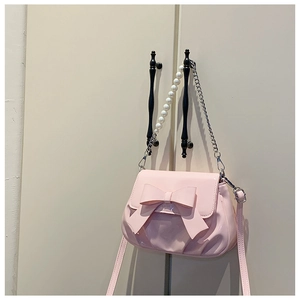 Detail view of pink bow handbag with elegant pearl handle and shiny faux leather texture
