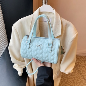 Sac à bandoulière cylindrique bleu clair avec matelassage en cœur et nœud argenté