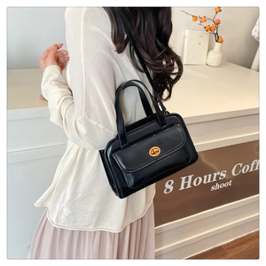 Detail of vintage black leather handbag with gold metal twist lock on a shoulder strap