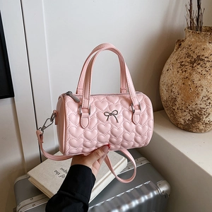 Sac à bandoulière cylindrique rose avec matelassage cœur et nœud argenté