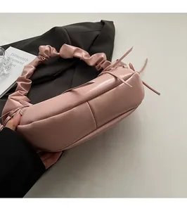 Détail de la poignée plissée rose et du ruban nœud sur le sac à bandoulière en cuir brillant
