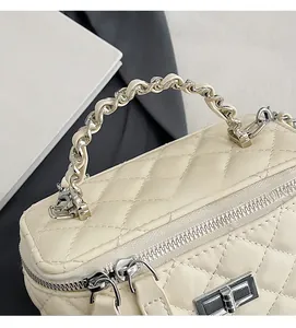 Detail of beige quilted mini handbag featuring chain handle and silver twist lock closure
