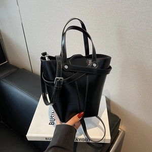 Classic black high-shine bucket bag with top handles and adjustable shoulder strap