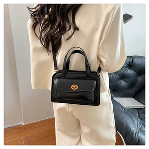 Detail of classic black leather handbag with gold twist lock on ivory suit background