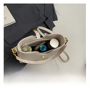 Detail showing the large interior capacity of this cream handbag with makeup items