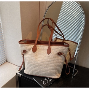 Detail view of woven straw tote bag with brown leather trim and side metal buckle accents