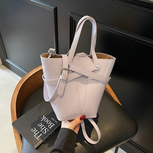 Light purple faux leather bucket bag with silver buckle and crossbody strap on chair