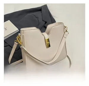 Detail of cream-colored bucket bag featuring a U-shaped top and golden metal twist lock