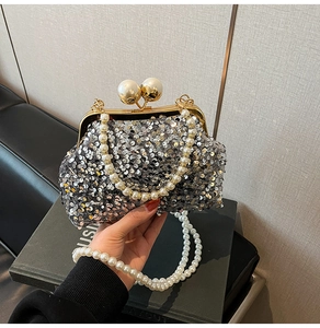 Détail d'un sac de soirée argenté à paillettes avec fermoir et poignée en perles