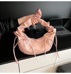 Détail d'un sac à main en cuir verni rose avec nœuds et poignée nuage froncée