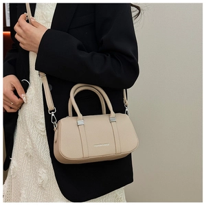 Detail of beige lychee leather boston bag with detachable strap worn by a model