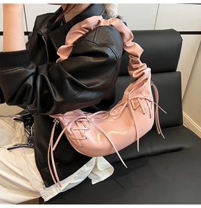 Détail du sac croissant rose brillant avec bandoulière à volants et lacets déco