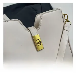 Close-up of golden rectangular metal lock and V-cut design on cream faux leather bag