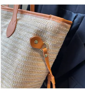 Detailed shot of golden hardware and leather trim on a woven straw tote bag
