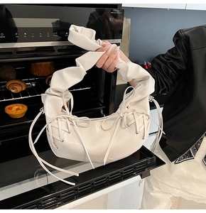 Détail du sac croissant blanc brillant avec nœud en ruban et poignée plissée