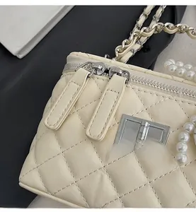 Detail of cream quilted handbag featuring pearl chain handle and silver hardware