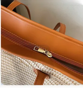 Detail of high-quality smooth gold metal zipper on woven tote bag with brown leather trim
