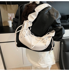 Détail du sac à bandoulière en cuir verni blanc avec bandoulière froncée et nœud