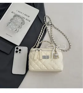 Detail of cream quilted chain bag with pearl bow charm and silver heart pendant