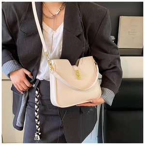 Detail of minimalist cream leather crossbody bag with elegant gold U-shaped lock hardware