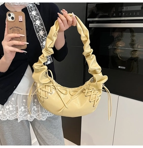 Détail d'un sac demi-lune jaune clair brillant avec nœud et poignée froncée élégante