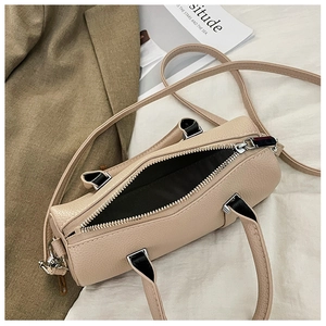 Detailed interior of a beige lychee leather cylindrical bag with silver hardware and zipper