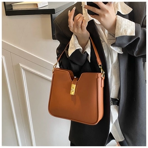 Macro shot of brown leather bucket bag with gold lock and deep U-shaped opening