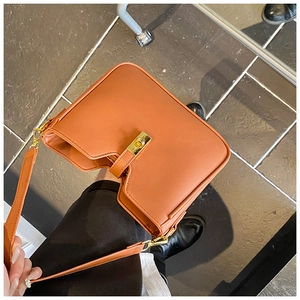 Detail of caramel leather shoulder bag with gold clasp and unique V-cut top design
