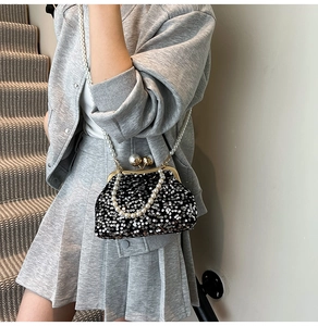 Détails de ce sac coquille en paillettes noires avec chaîne en perles et fermoir métallique